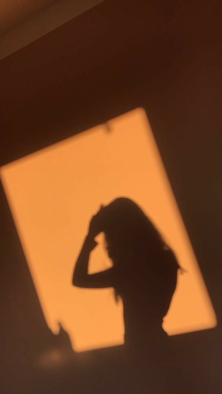 A shadow of someone holding their hair in the sun - Shadow