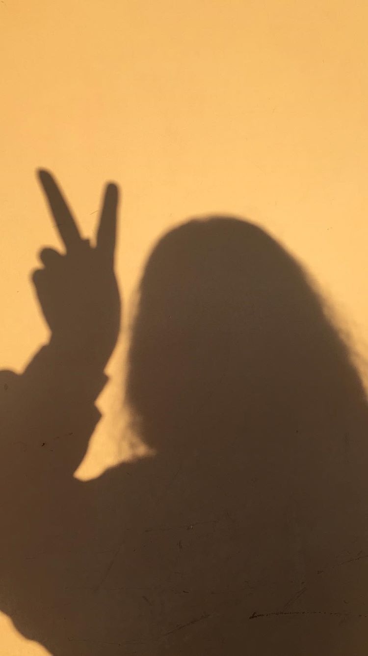 A shadow of a woman making a peace sign - Shadow