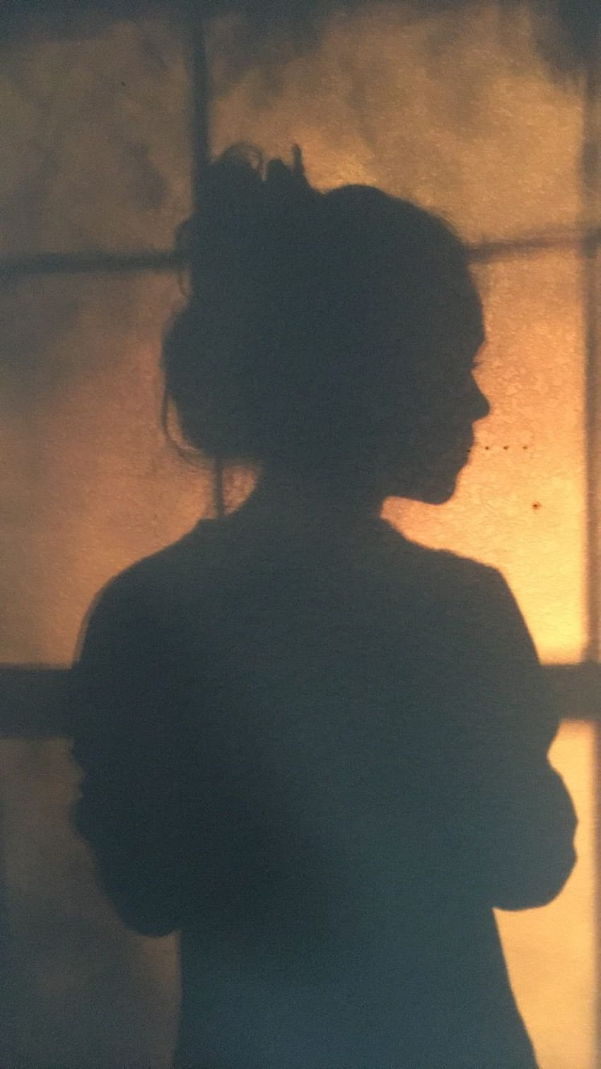 A woman standing in front of an open window - Shadow