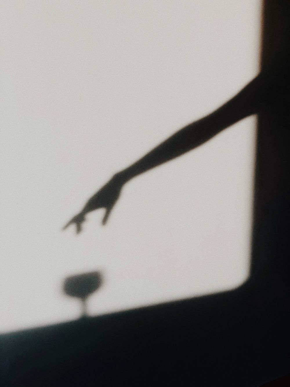 A shadow of a hand reaching out to a glass - Shadow