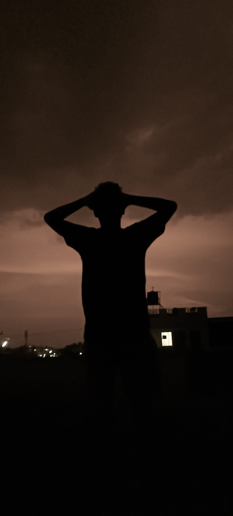 A man standing in the dark with his hands on top of head - Shadow