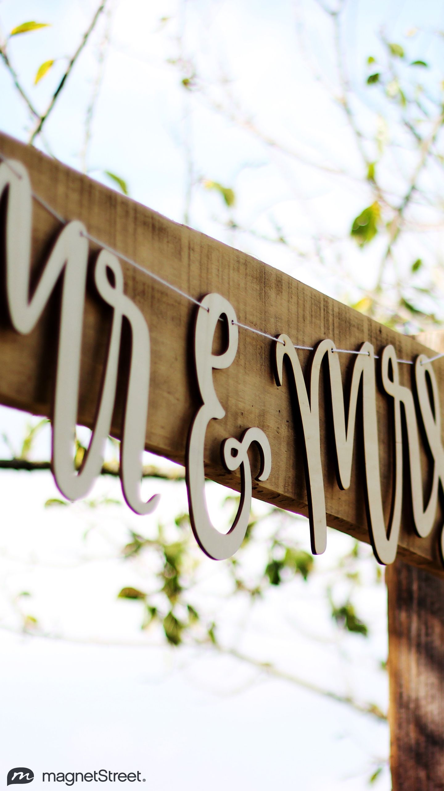 A wooden sign that says Mr. and Mrs. hanging from a tree. - Wedding