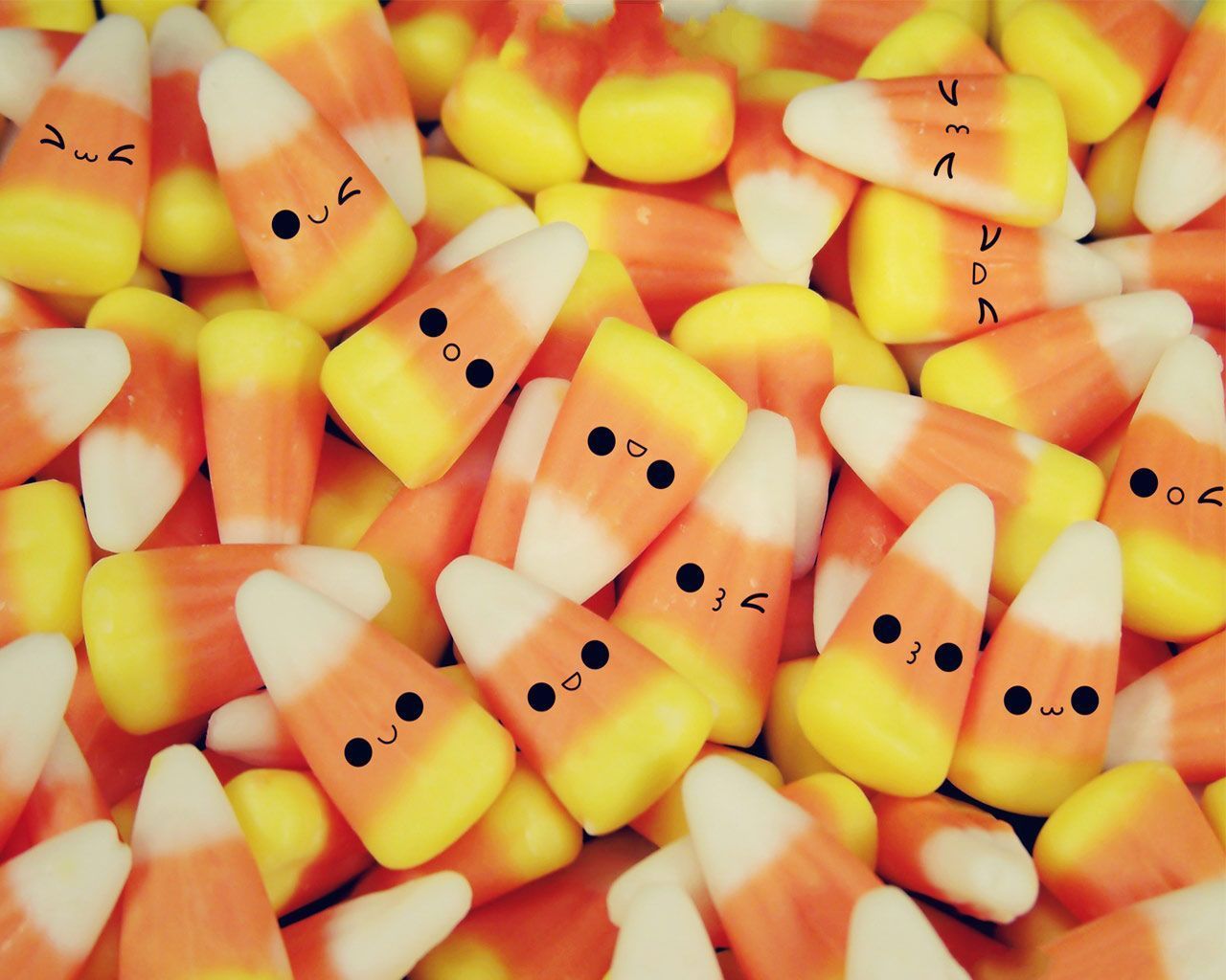 A pile of candy corn with faces drawn on them - Candy