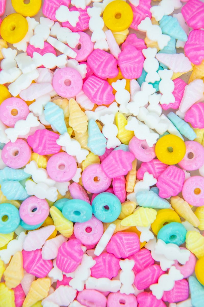 A close up of colorful candies in pink, yellow, blue, and white. - Candy