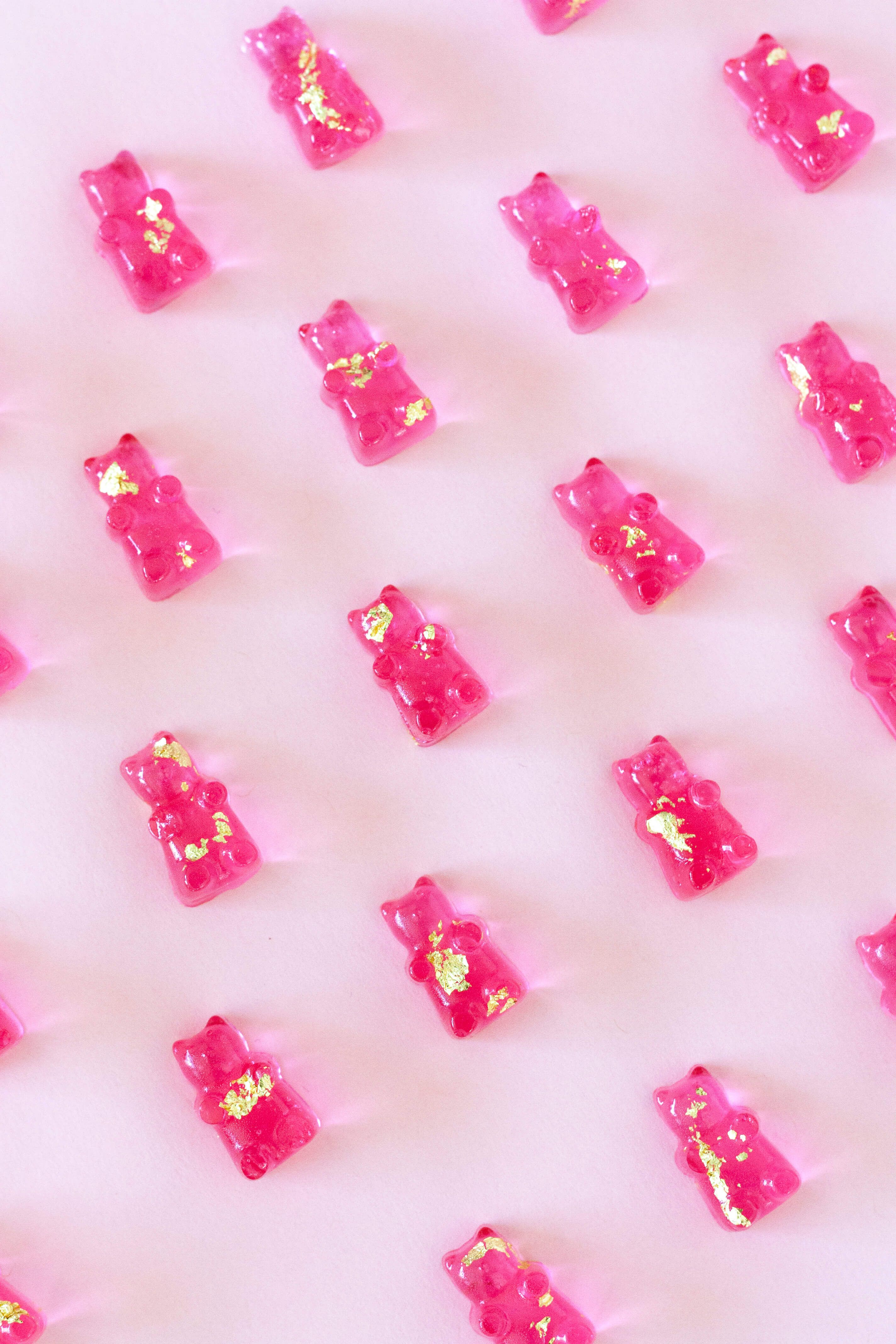 Pink gummy bears with gold flakes on a pink background - Candy