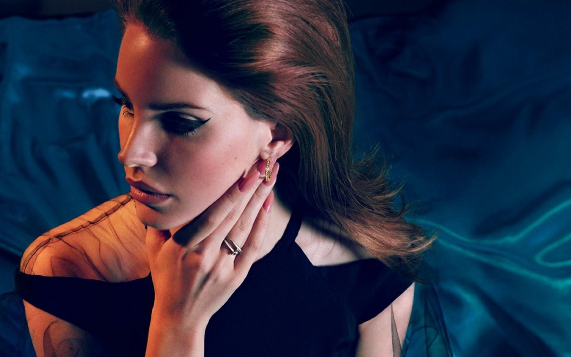 A woman with brown hair and a black top with a gold ring on her left hand ring finger. - Lana Del Rey