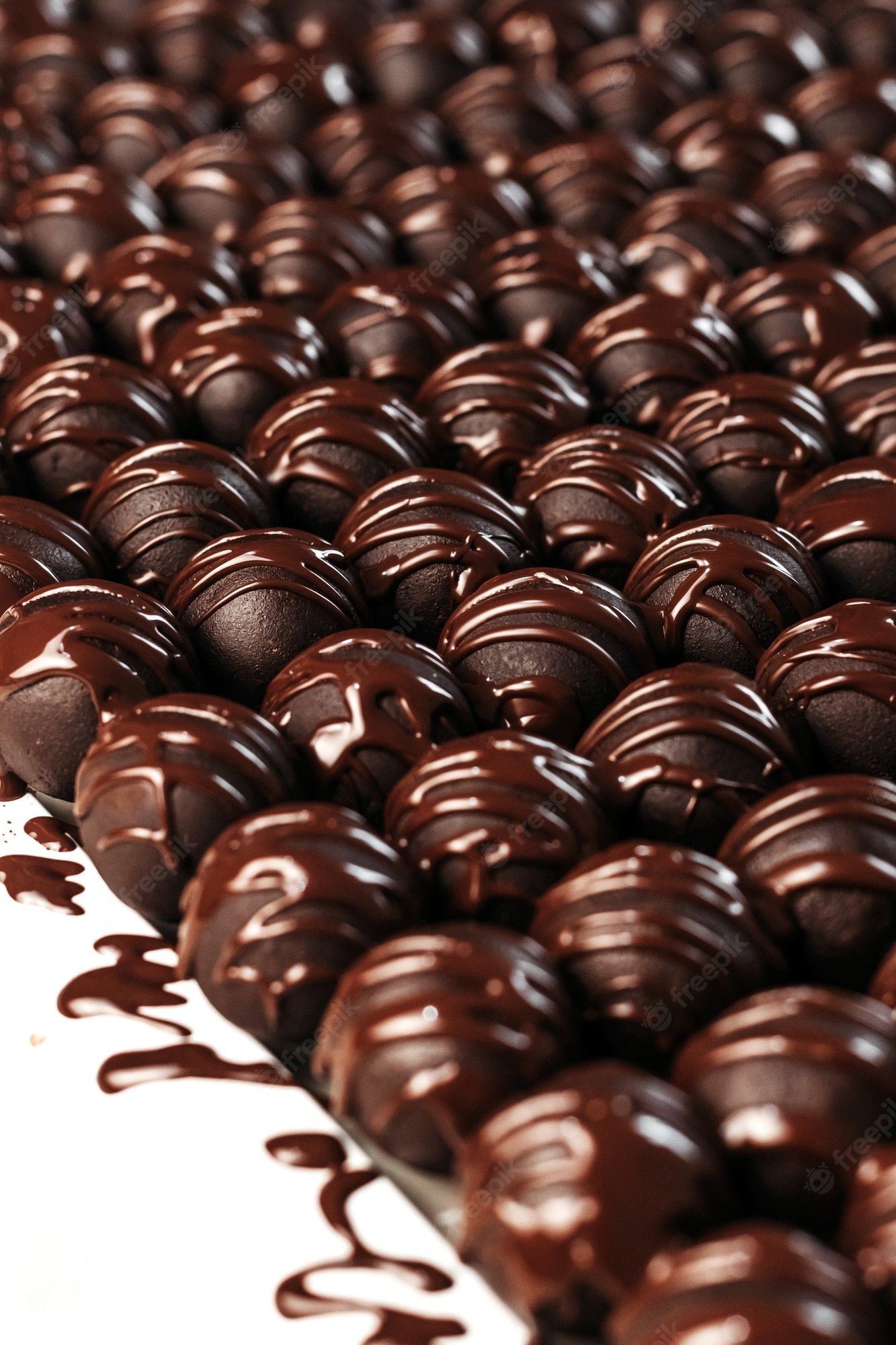 A tray of chocolate truffles with some coated in chocolate sauce. - Candy, chocolate