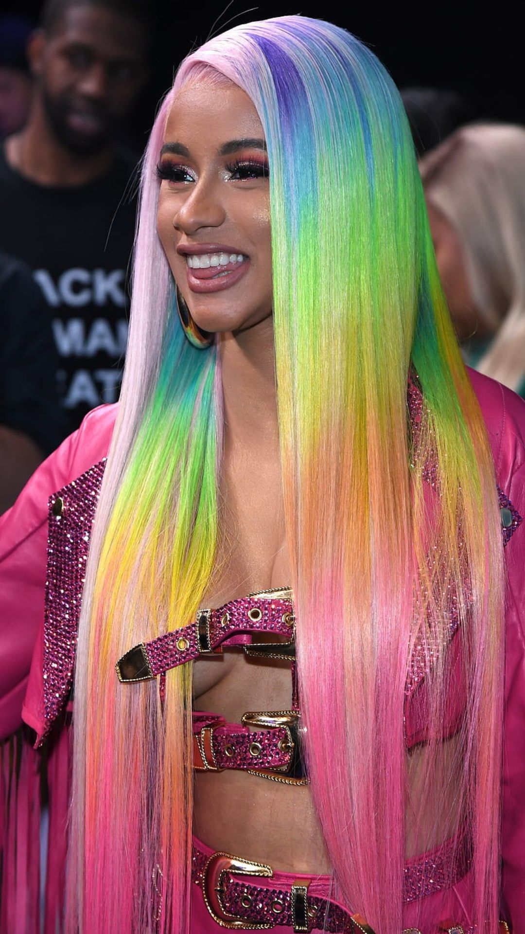 A woman with long rainbow hair and pink lipstick - Cardi B