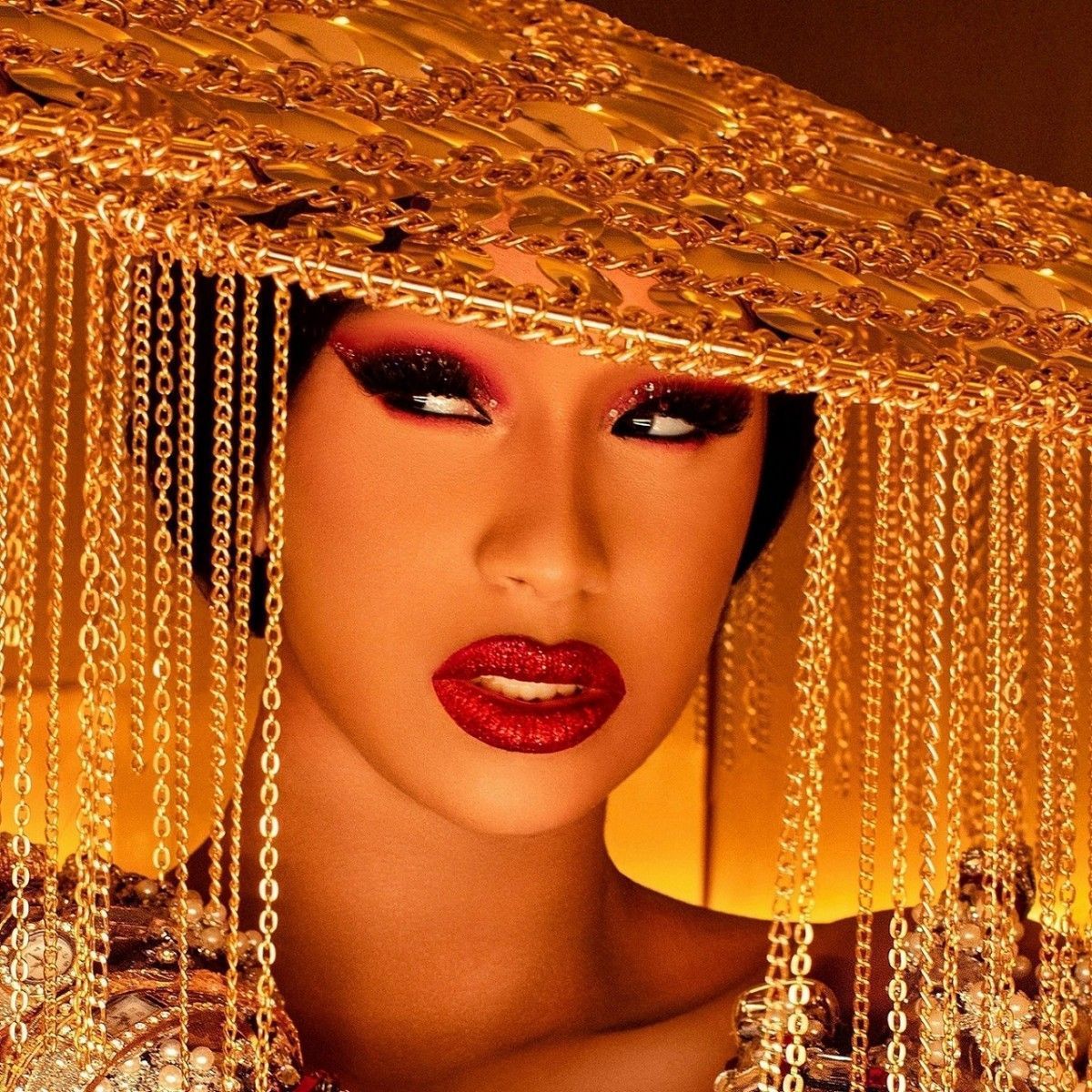 A woman with gold makeup and jewelry - Cardi B