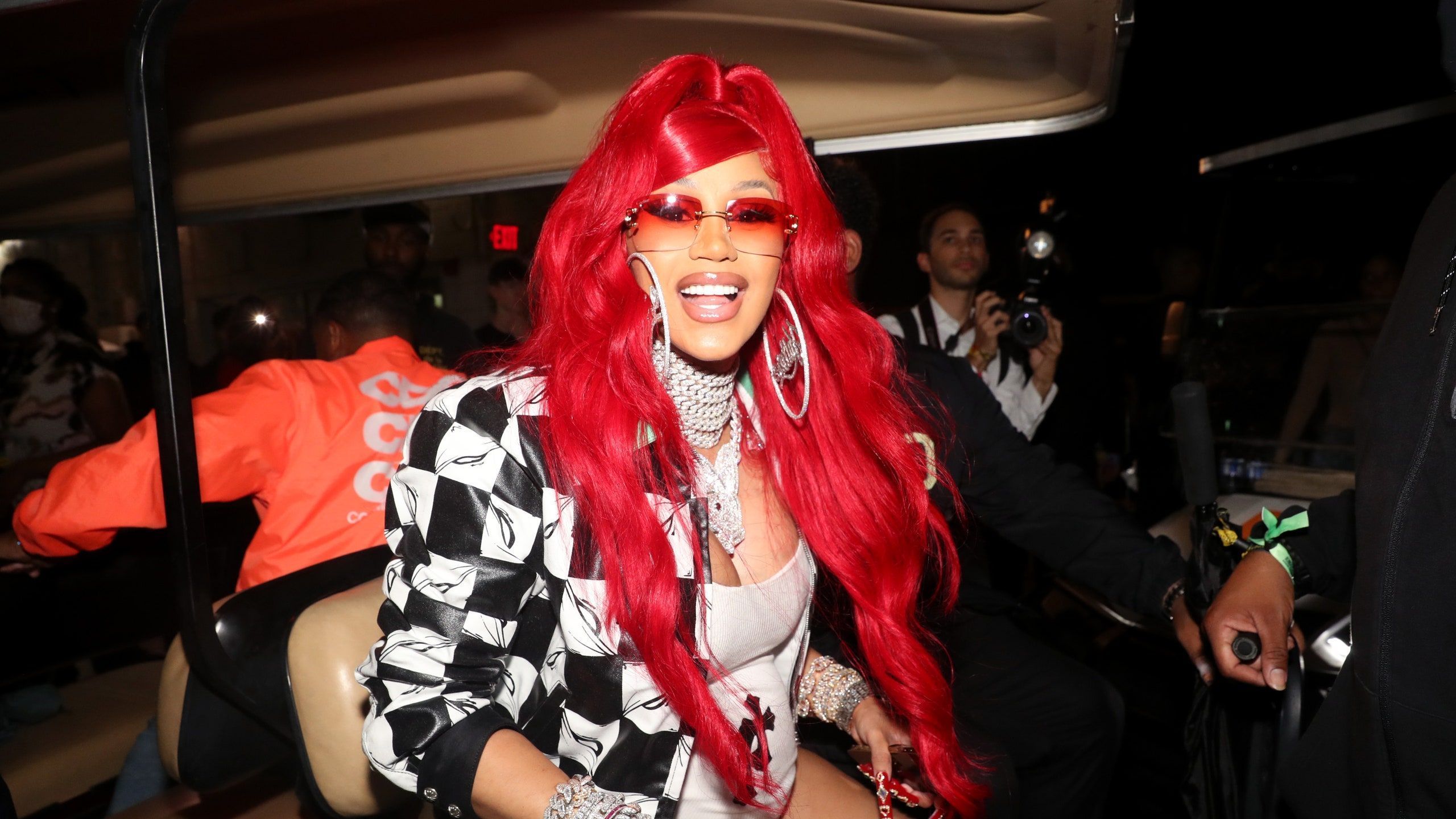 A woman with red hair and glasses is smiling - Cardi B