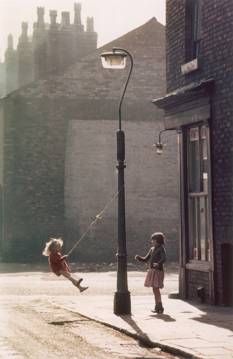 Two girls play on a swing in the street - 60s