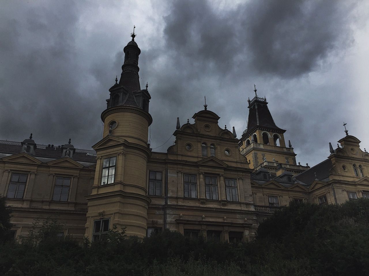 A large building with a tower and a cloudy sky above it. - Dark academia
