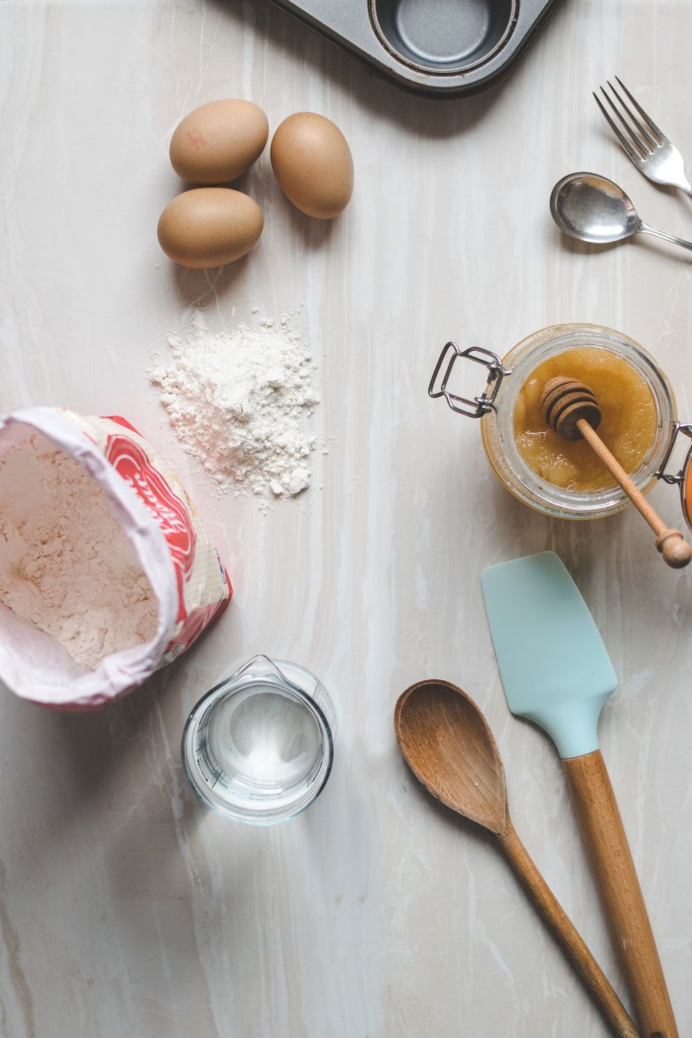 A table with eggs, flour, and other baking supplies on it. - Bakery