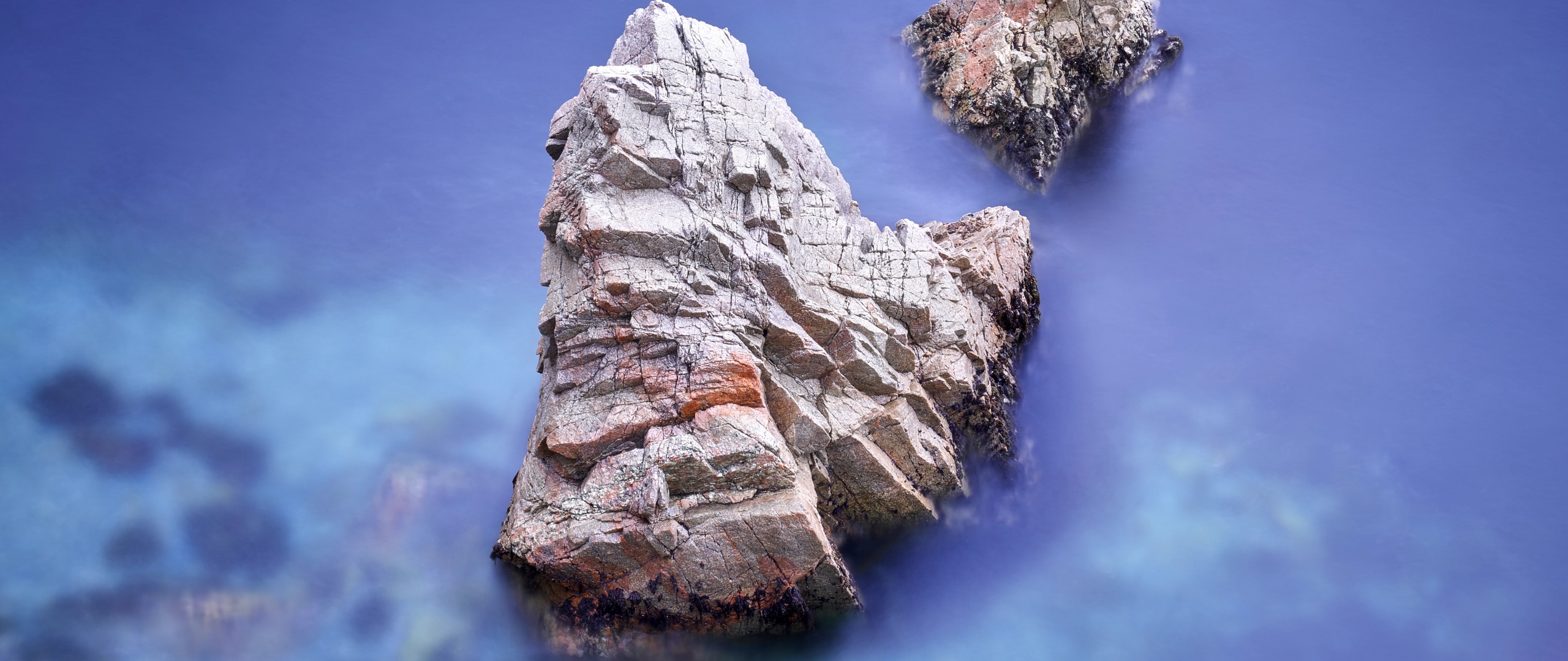 A rock formation jutting out of the ocean - Rocks