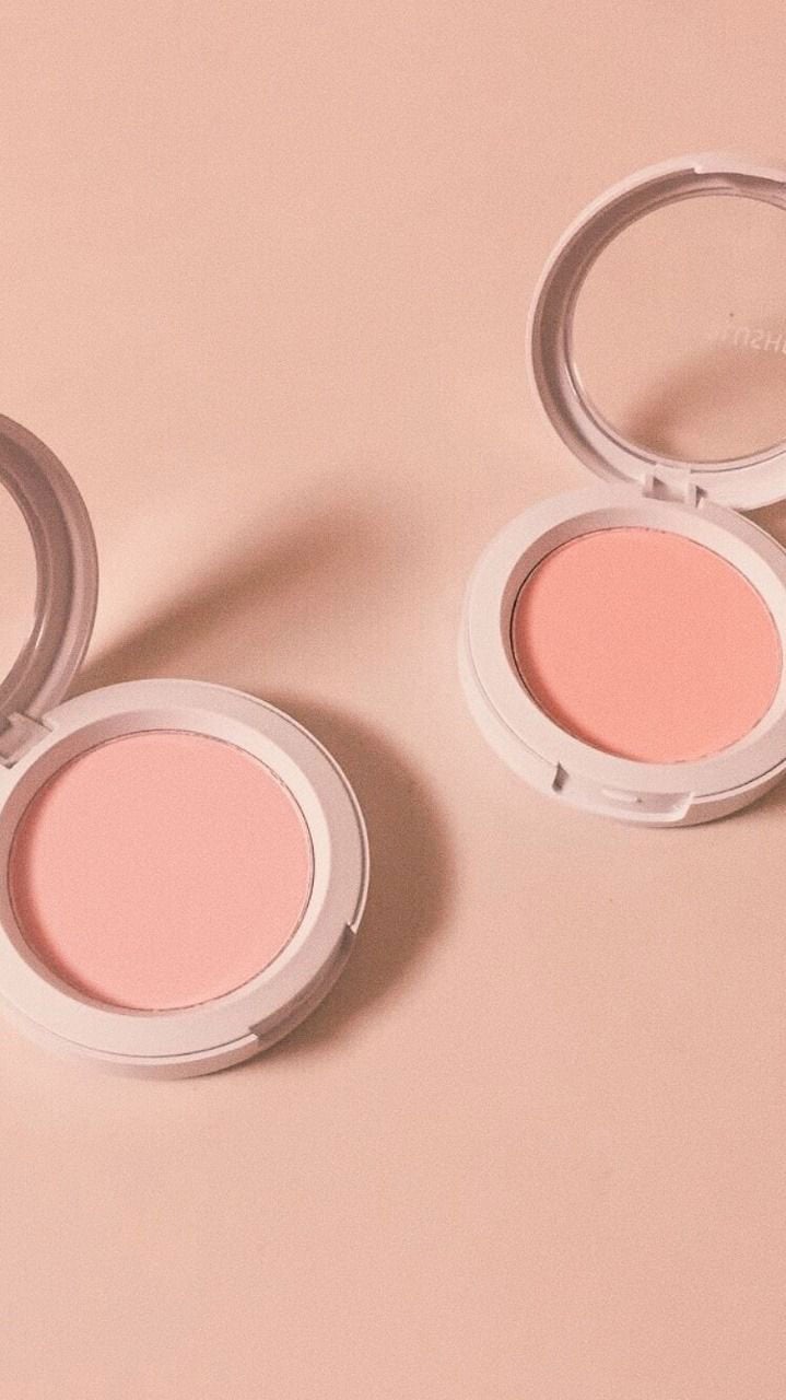 Two compacts of pink blush sitting on a table - Blush, makeup