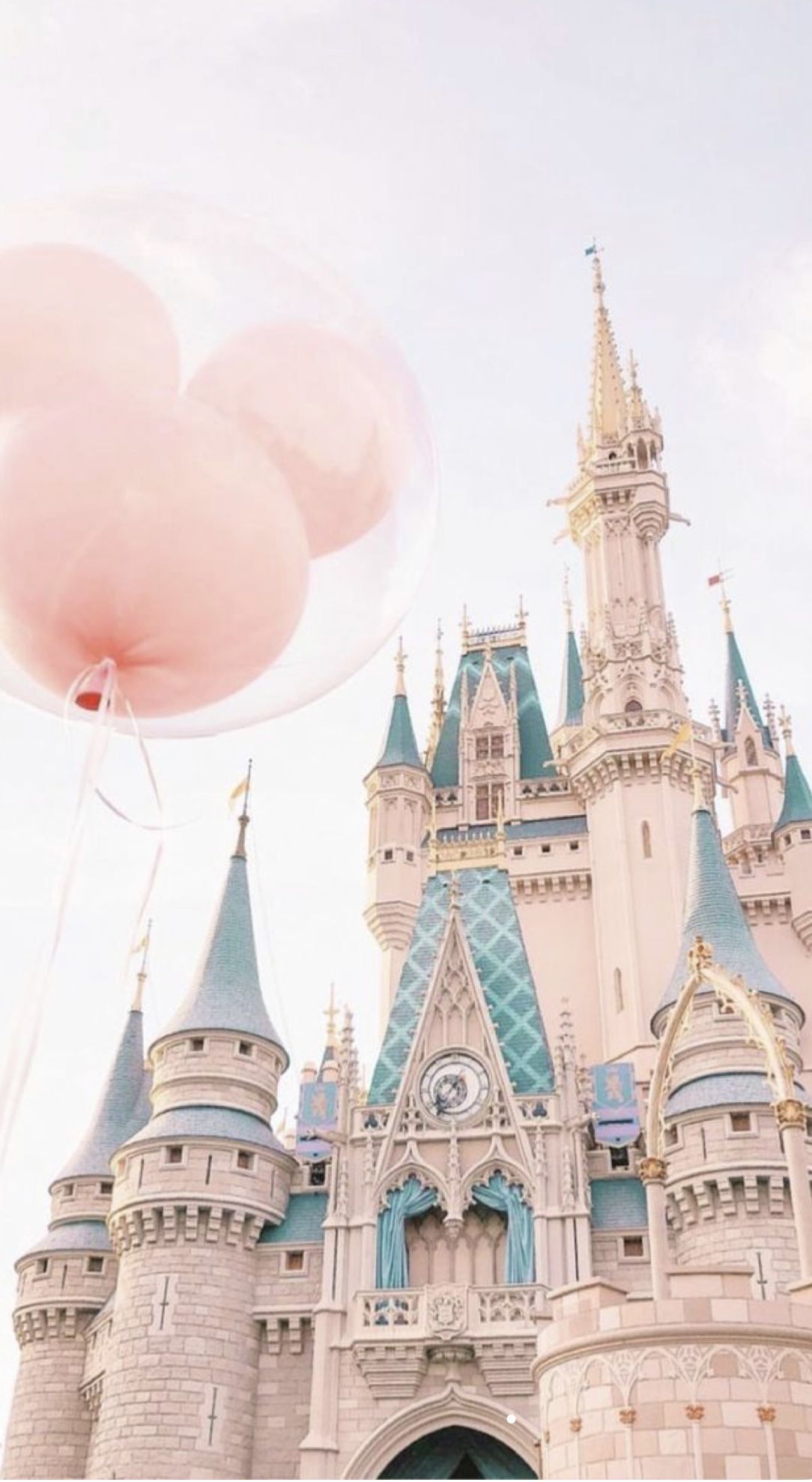 A balloon in the shape of pink hearts is held by someone - Disneyland, castle, Disney, balloons