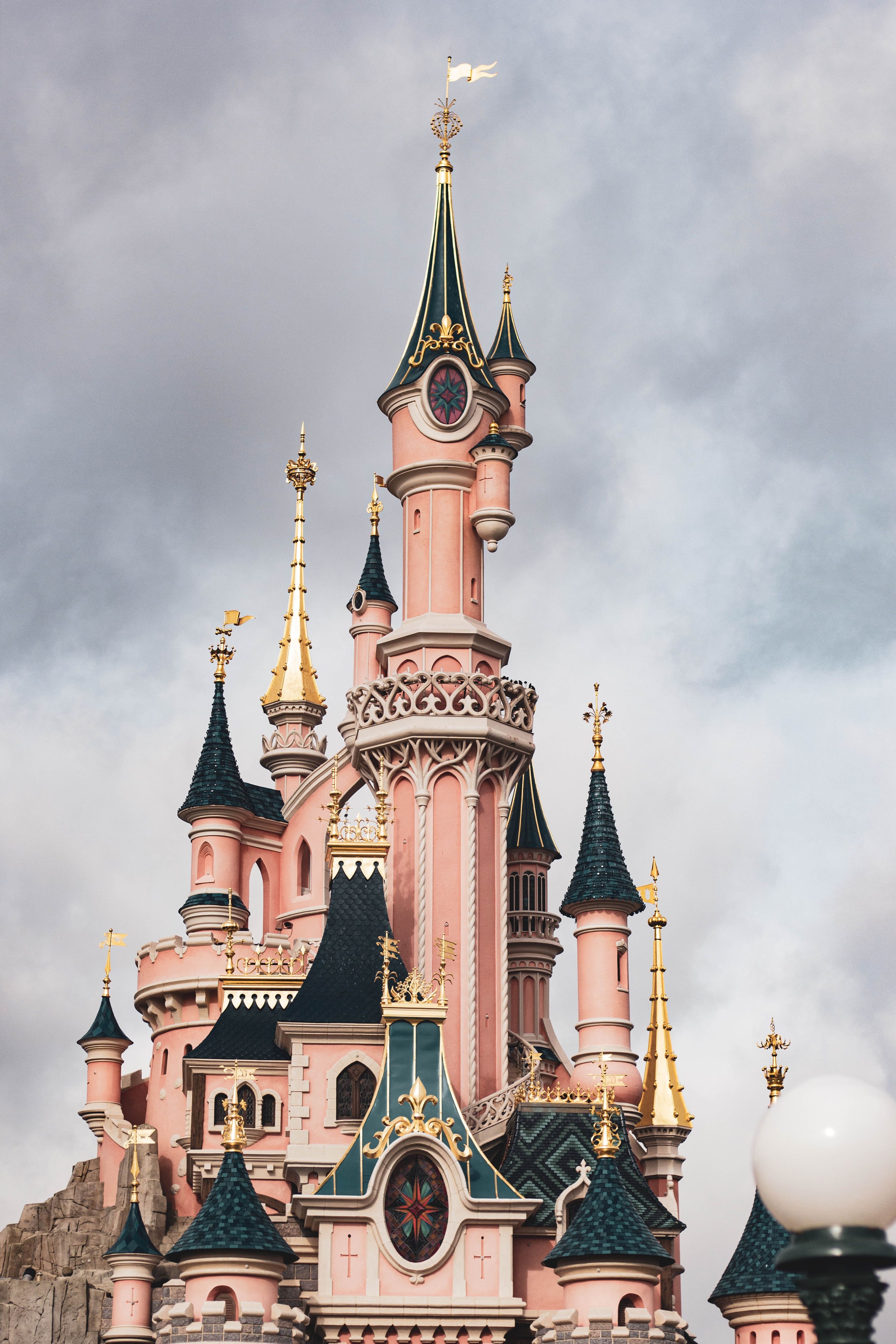 A large pink castle with clock tower - Castle, Disneyland