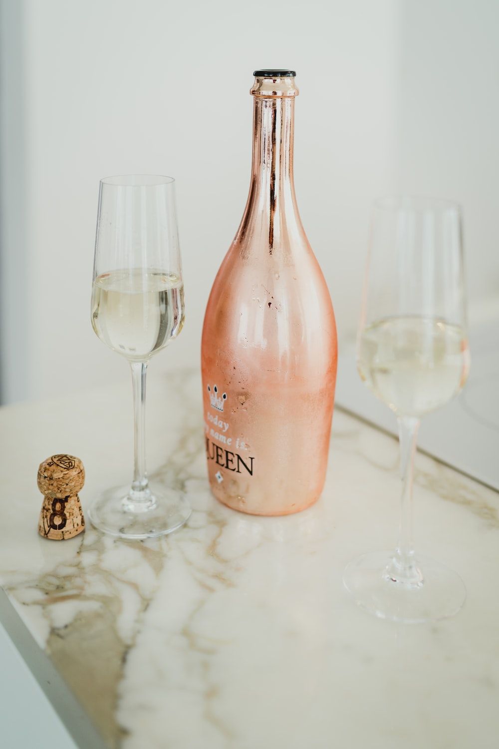 A bottle of Queen Cuvée with two glasses of champagne on a marble table. - Champagne