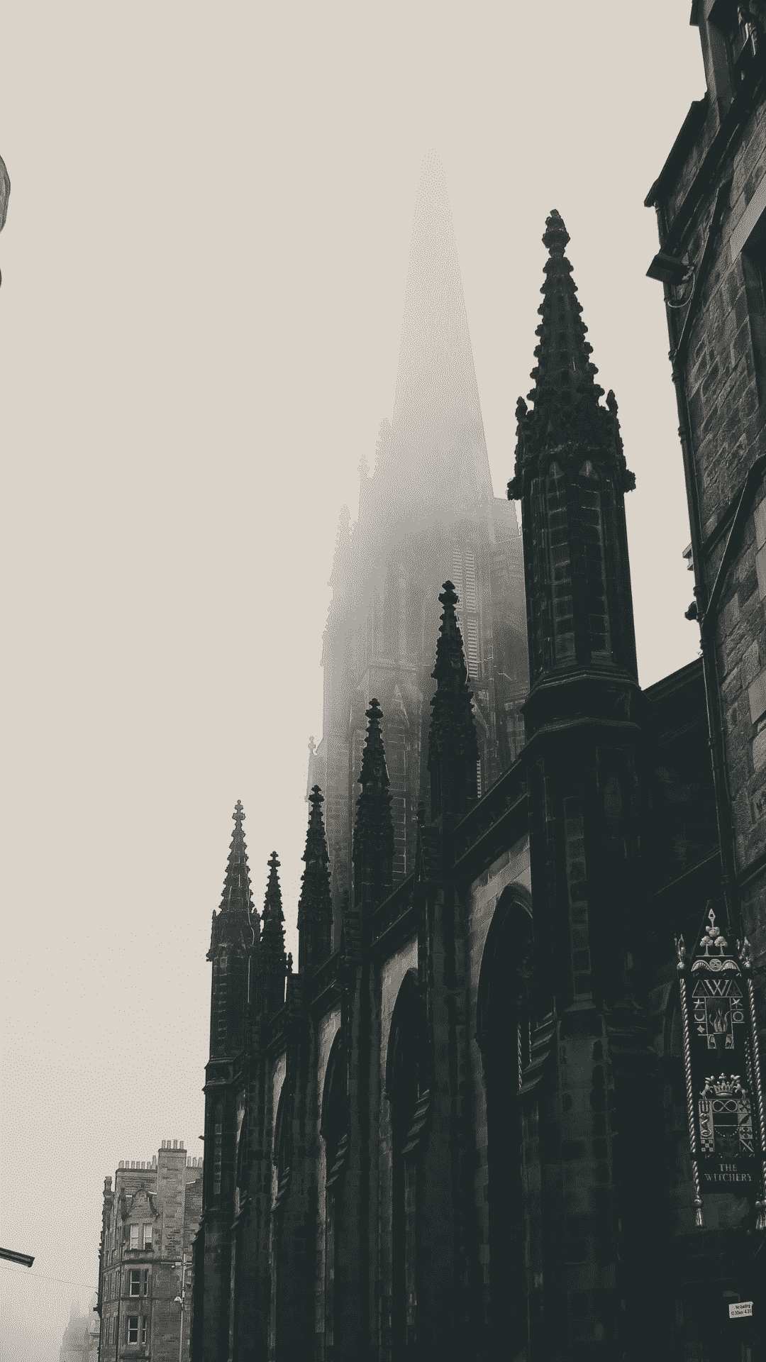A black and white photo of a large building with a tower and many spires, all of which are covered in fog. - Castle