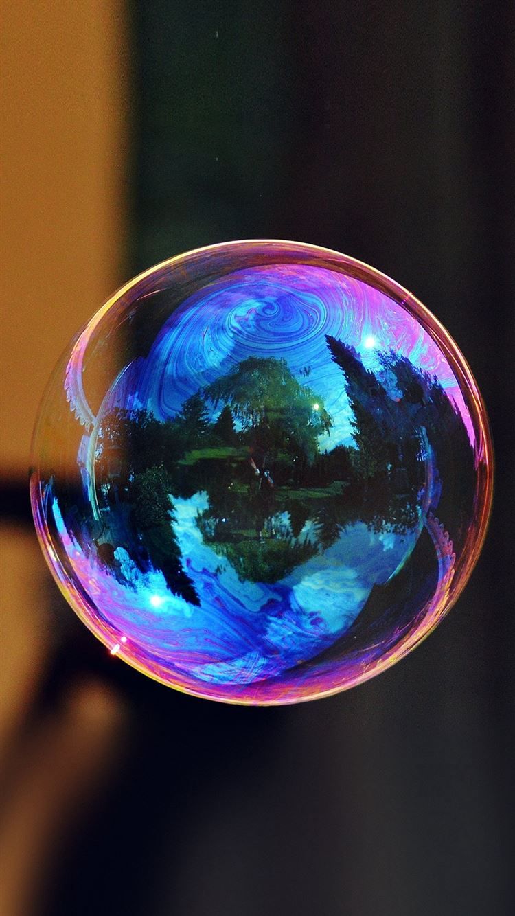 A soap bubble with a beautiful reflection of the sky and trees - Bubbles