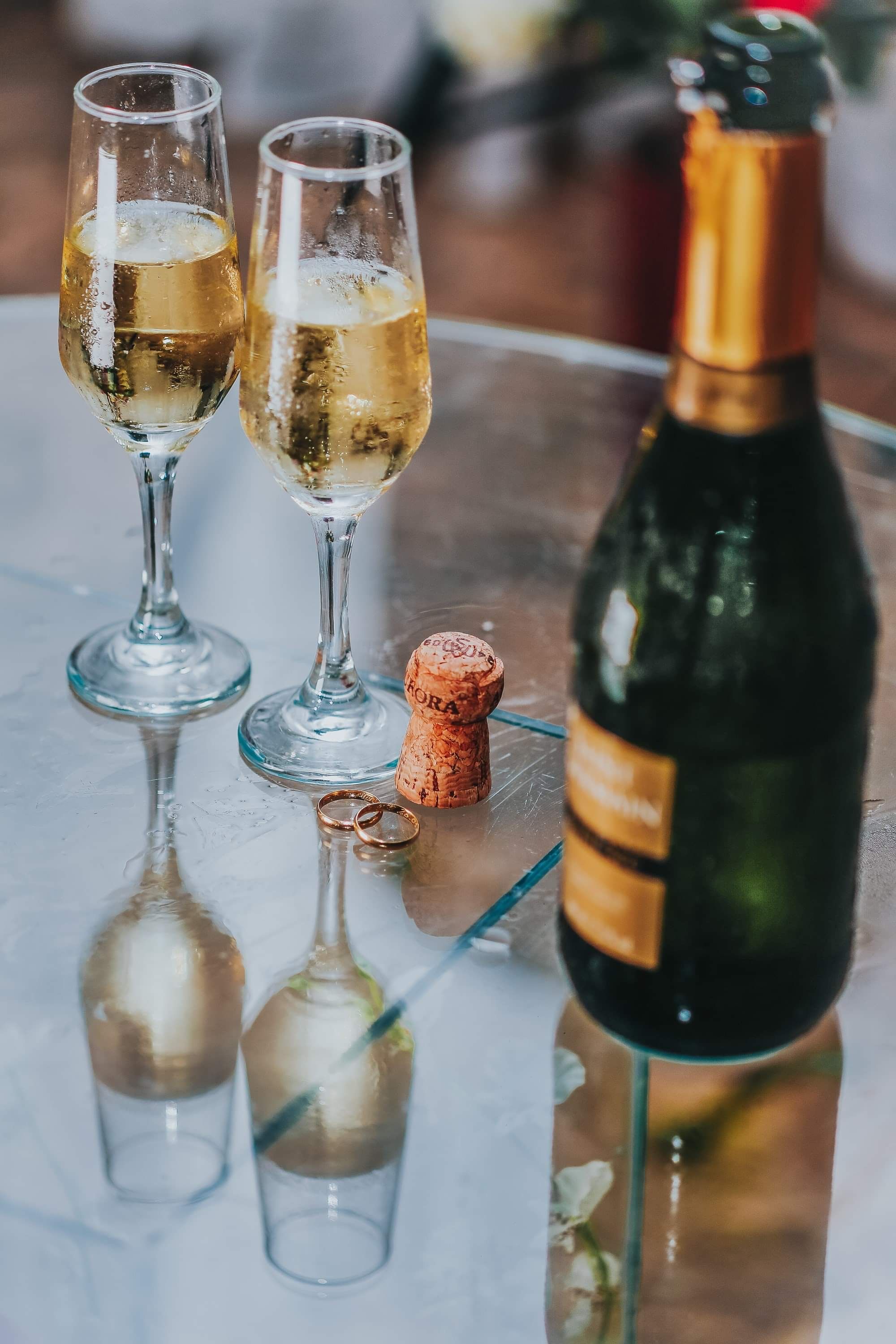 A glass table with two wine goblets and an empty bottle - Champagne