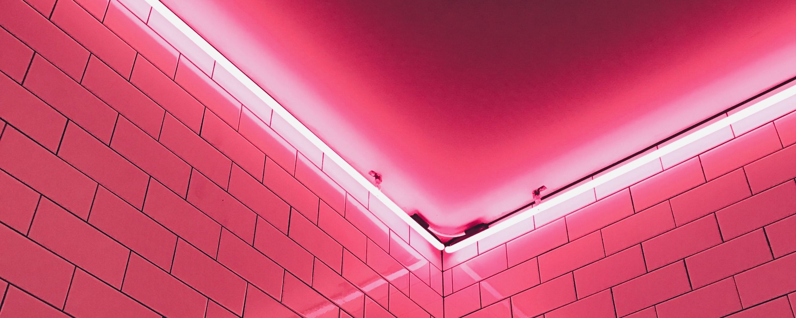 A pink neon light shines on a white tiled wall. - Light pink