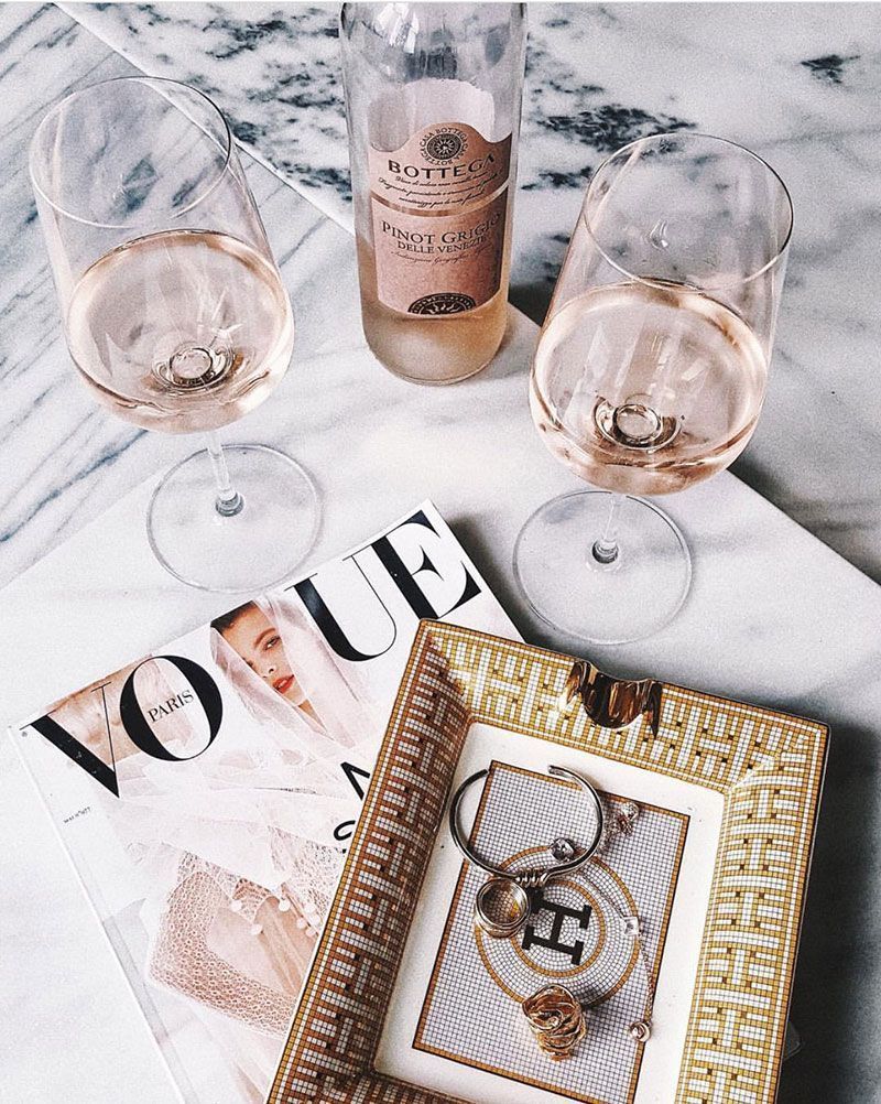 Two glasses of wine next to a Vogue magazine on a marble table. - Champagne