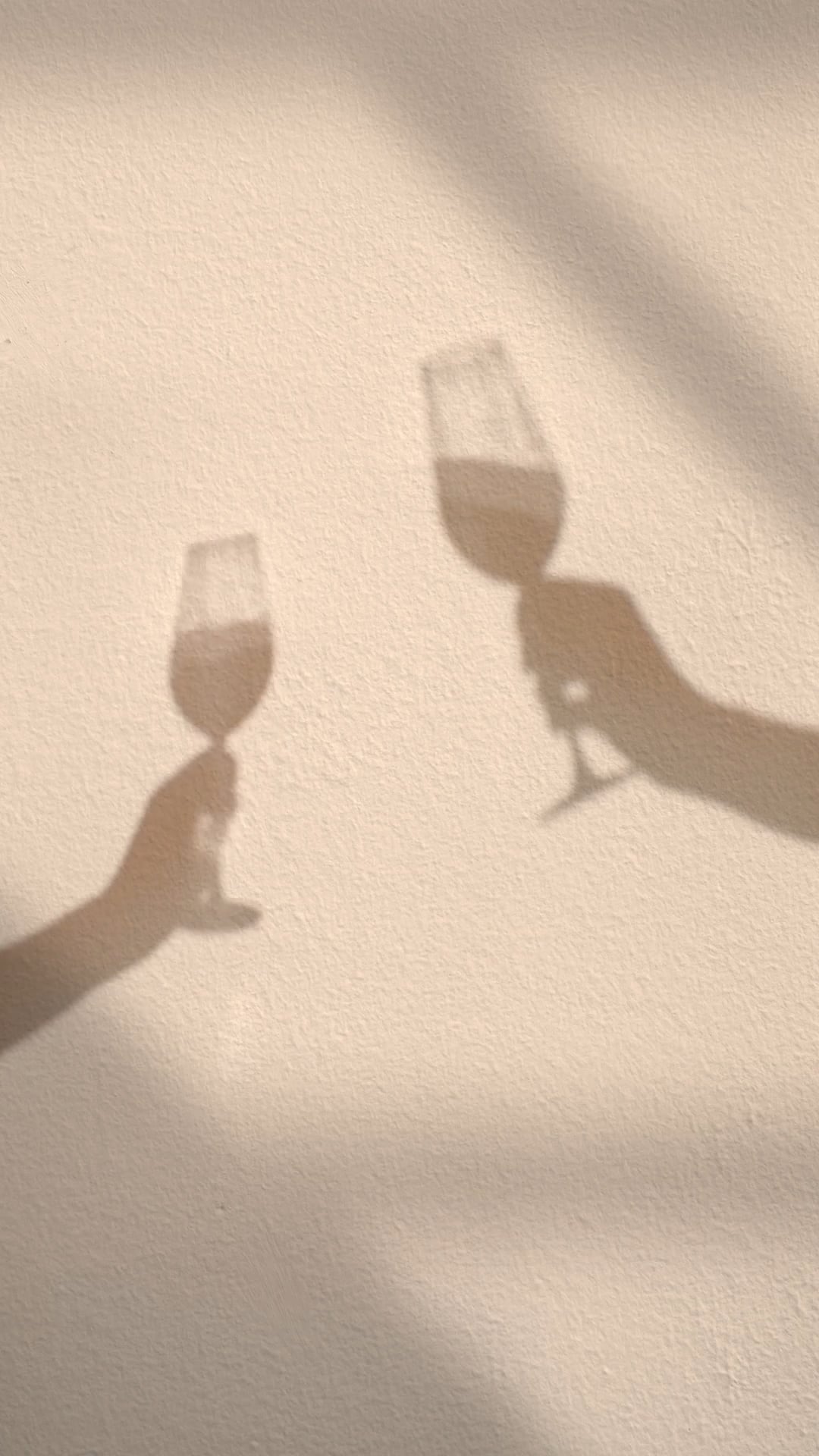 A picture of two hands holding wine glasses against a white wall. - Champagne