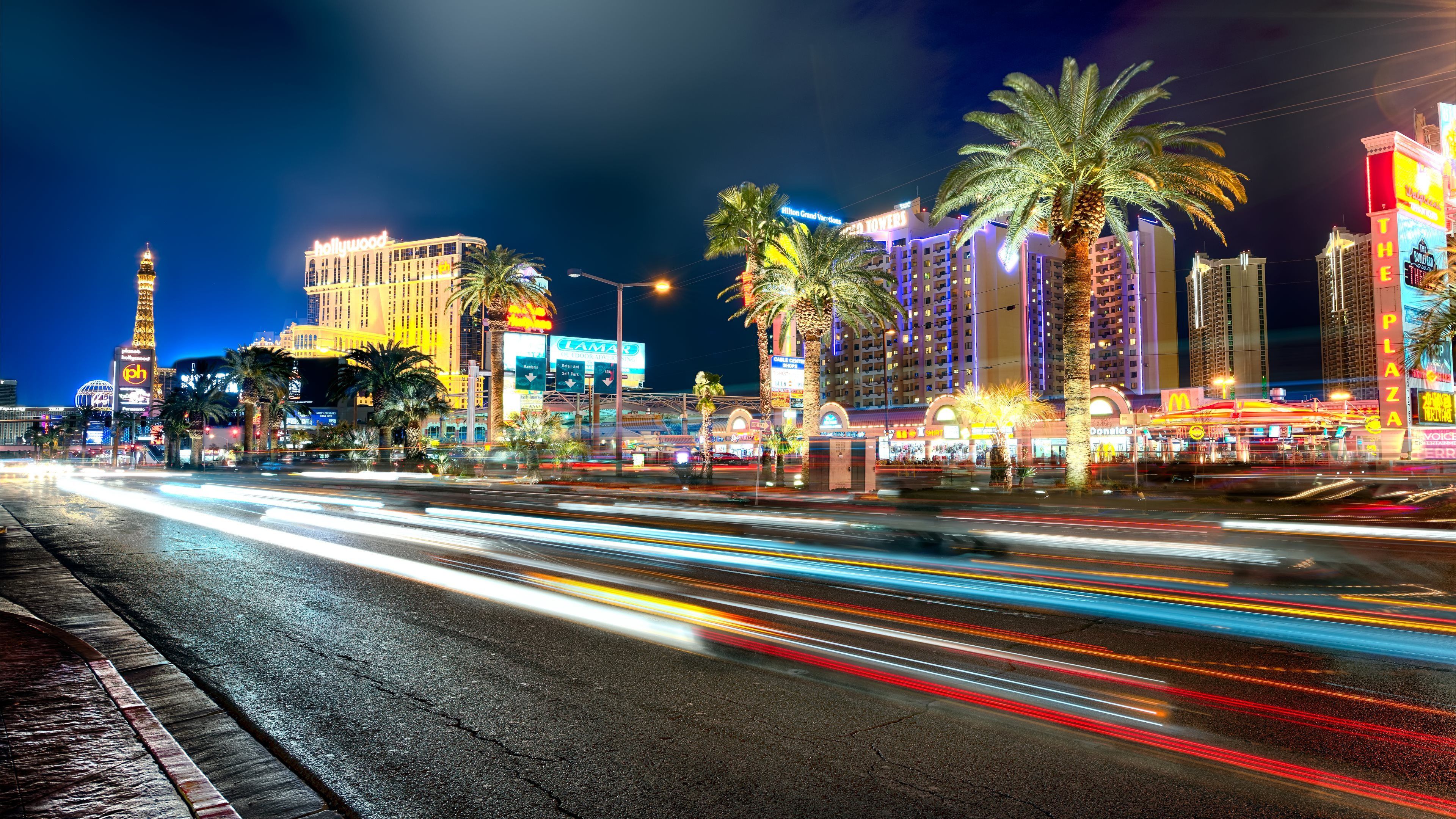 A busy street in Las Vegas with palm trees and neon lights. - Las Vegas