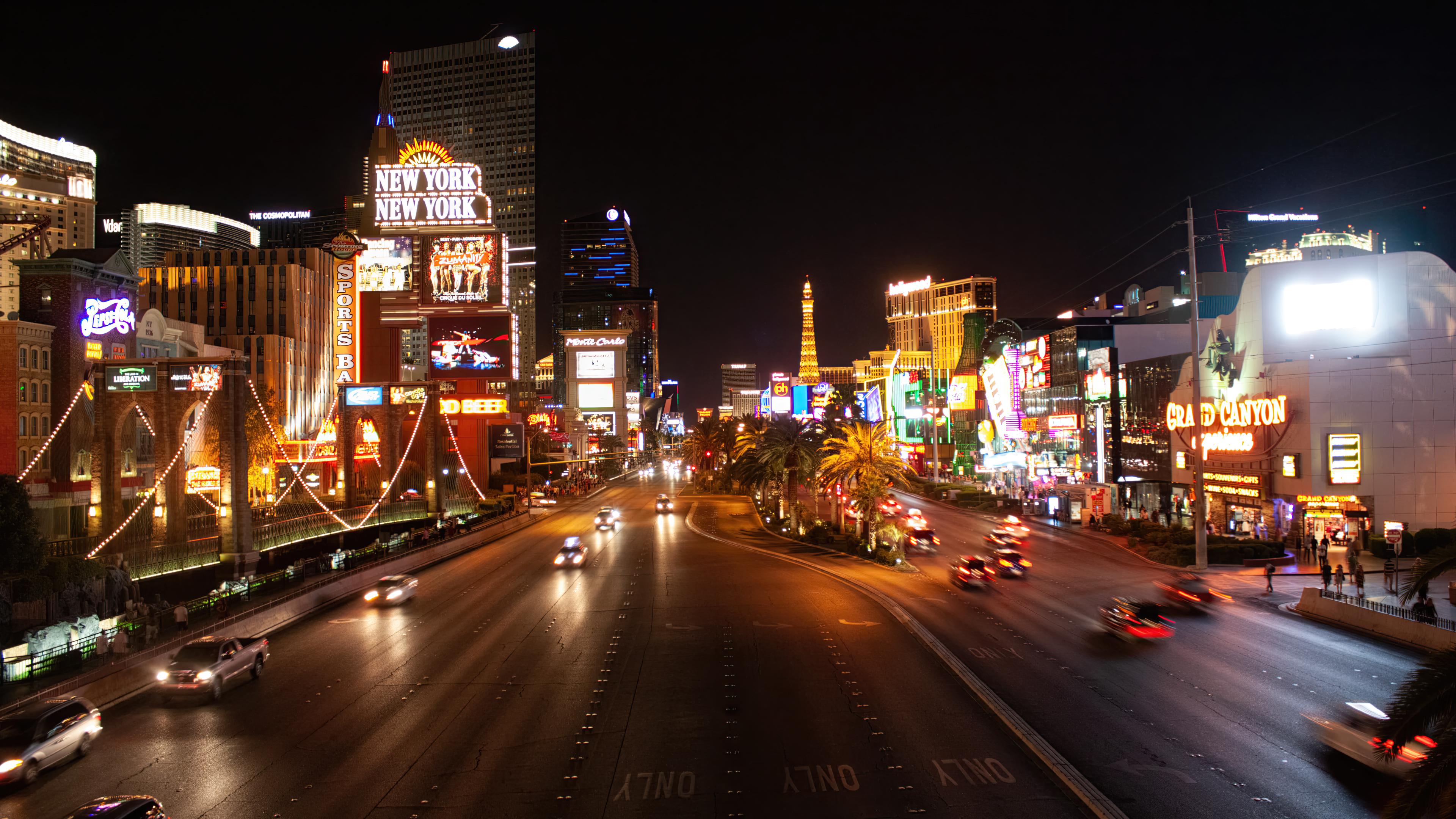 A city street at night with cars and neon lights. - Las Vegas