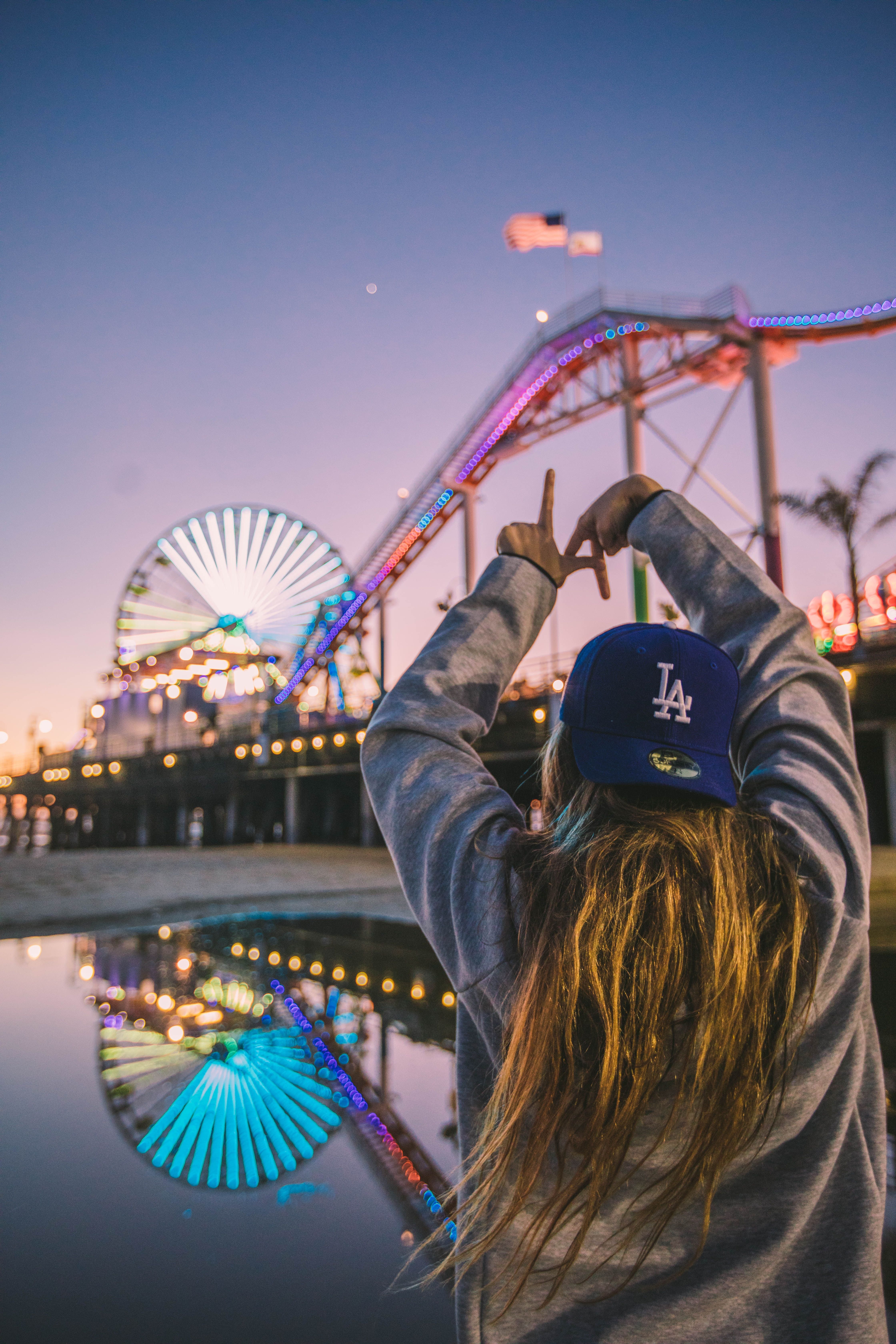 A woman in a blue baseball cap standing in front of a ferris wheel - Los Angeles, California