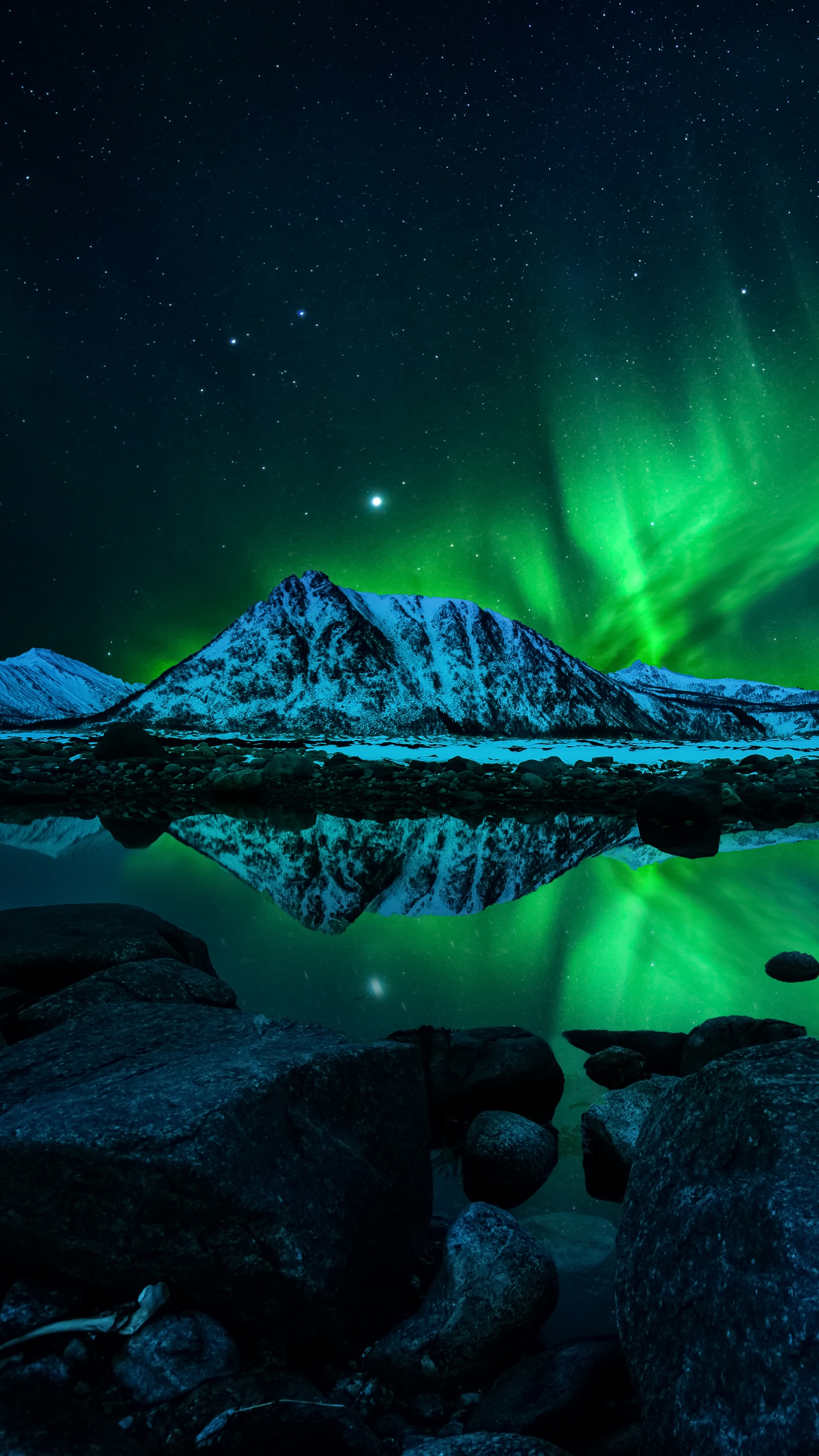 Northern lights over a lake with mountains in the background - Rocks