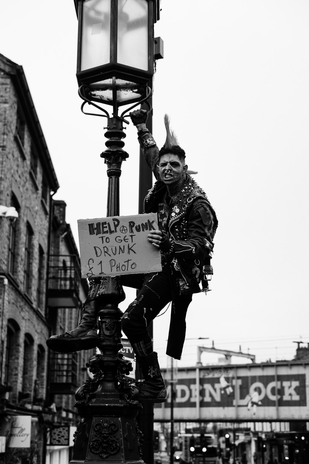 A man dressed as a punk rock monster poses on a lamp post - Punk
