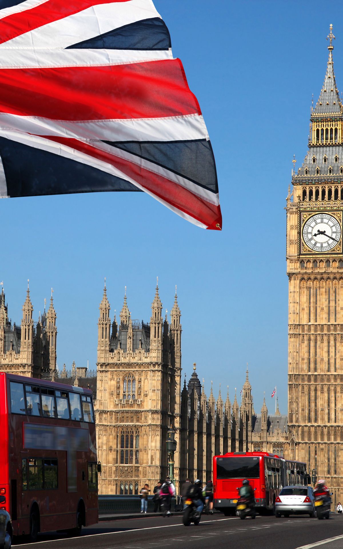 A red double decker bus driving down a street with Big Ben in the background. - London