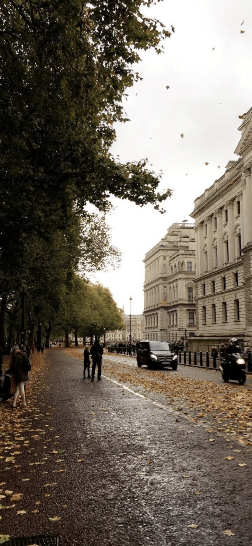 A street with people walking on the sidewalk and cars parked on the side. - London