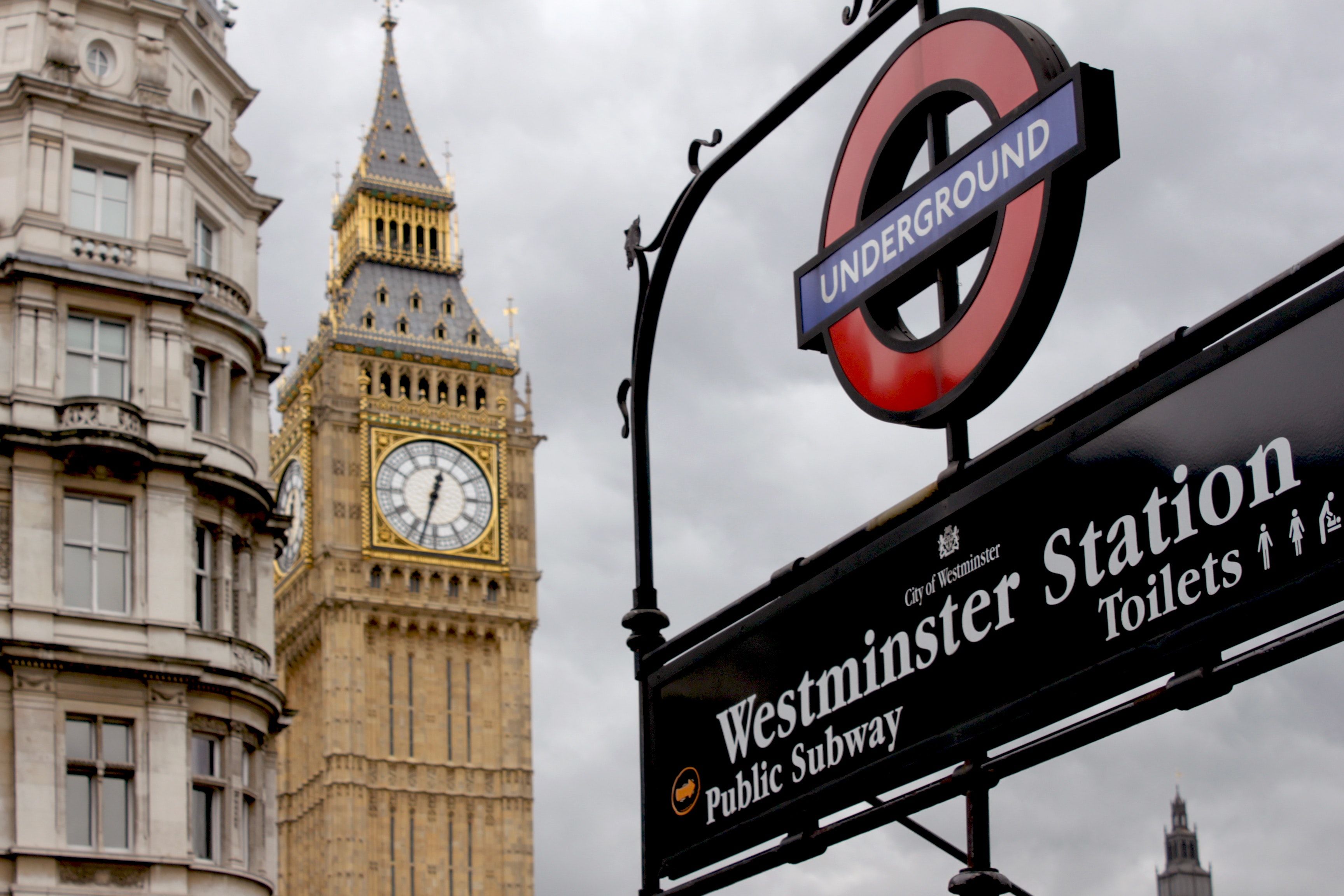 A clock tower and sign in front of two buildings - London