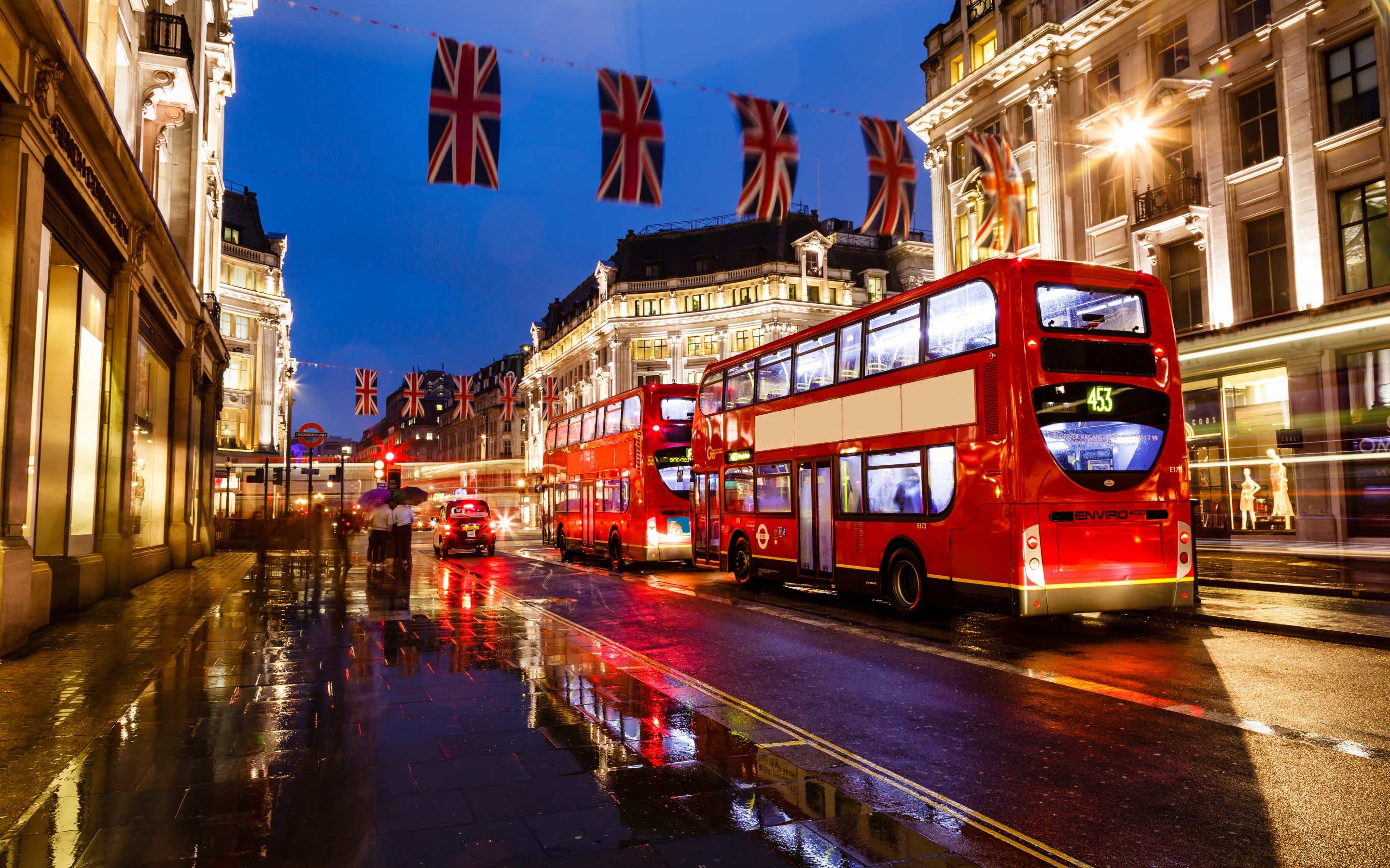 Red double decker buses on a wet Regent Street at night - London