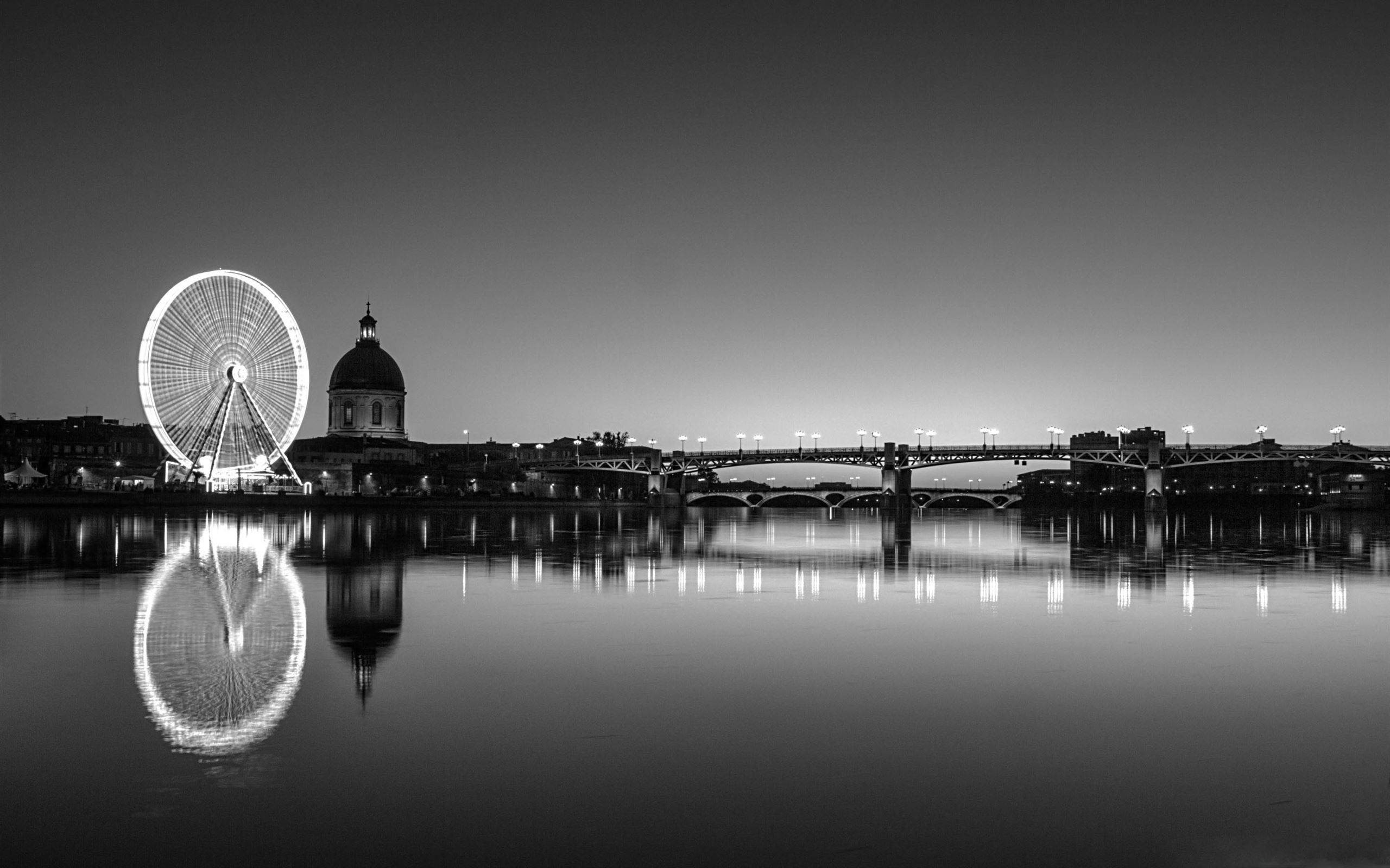 A black and white photo of a Ferris wheel and bridge over water. - London