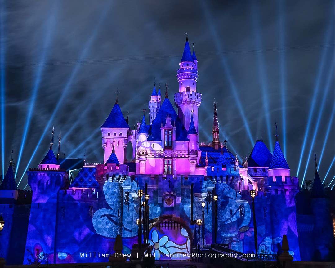 The castle at disneyland is lit up with purple and blue lights - Minnie Mouse, Disneyland