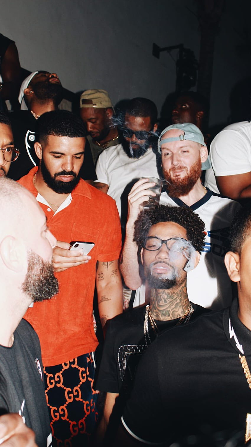 A group of men, including rappers Drake andOffset, smoke and drink at a party. - Drake