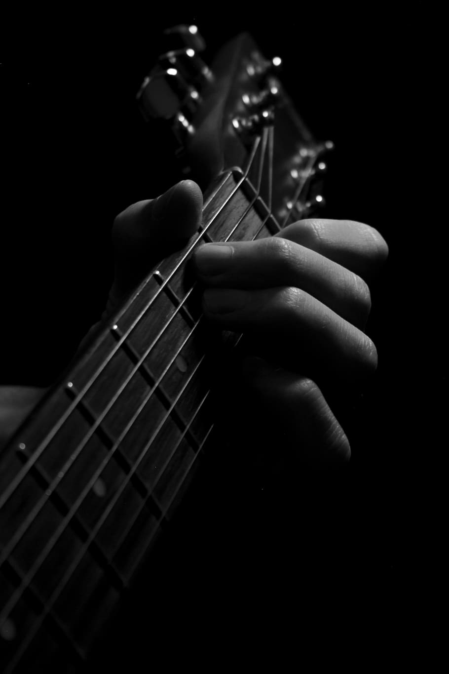 A person's hand playing a guitar in black and white. - Guitar