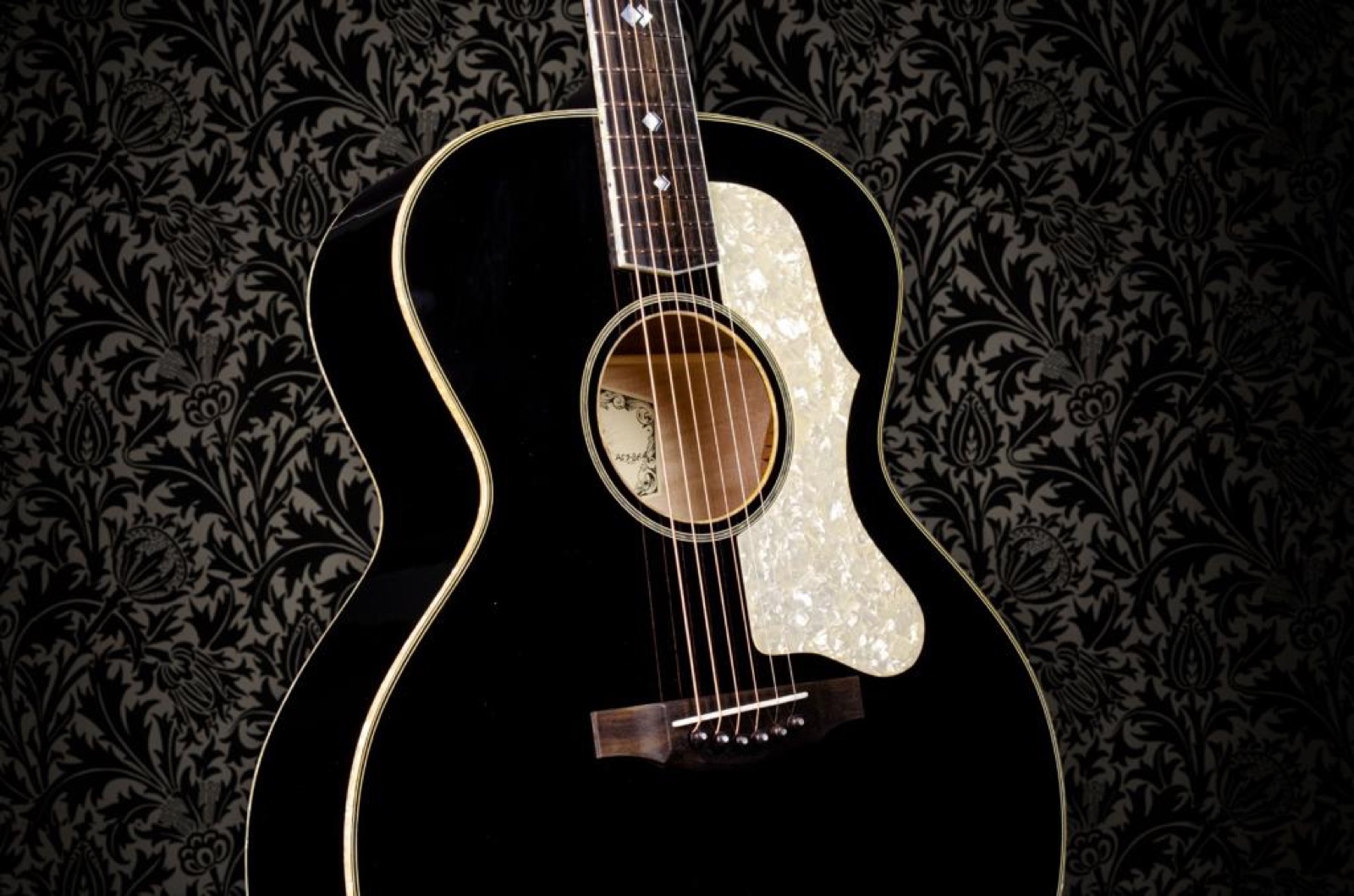 A black guitar sitting on top of an old wooden table - Guitar