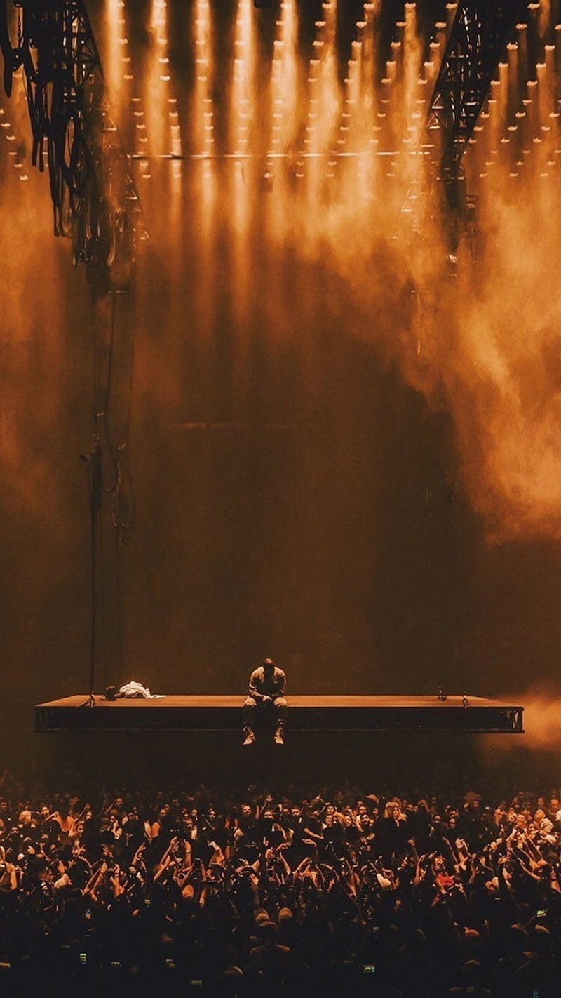 A concert with smoke and people in the background - Kanye West