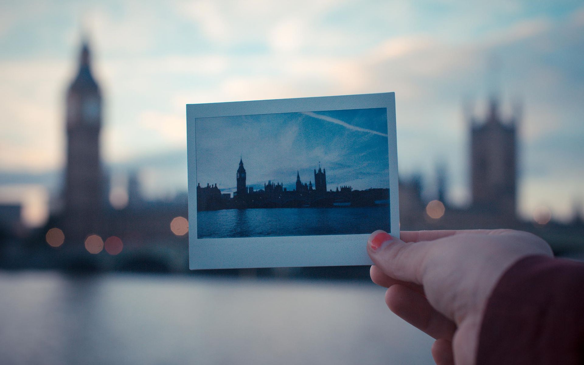 A person holding up an old photo of london - Polaroid