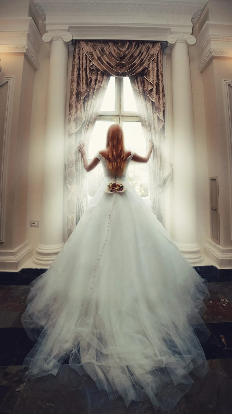 A woman in white dress standing at window - Wedding