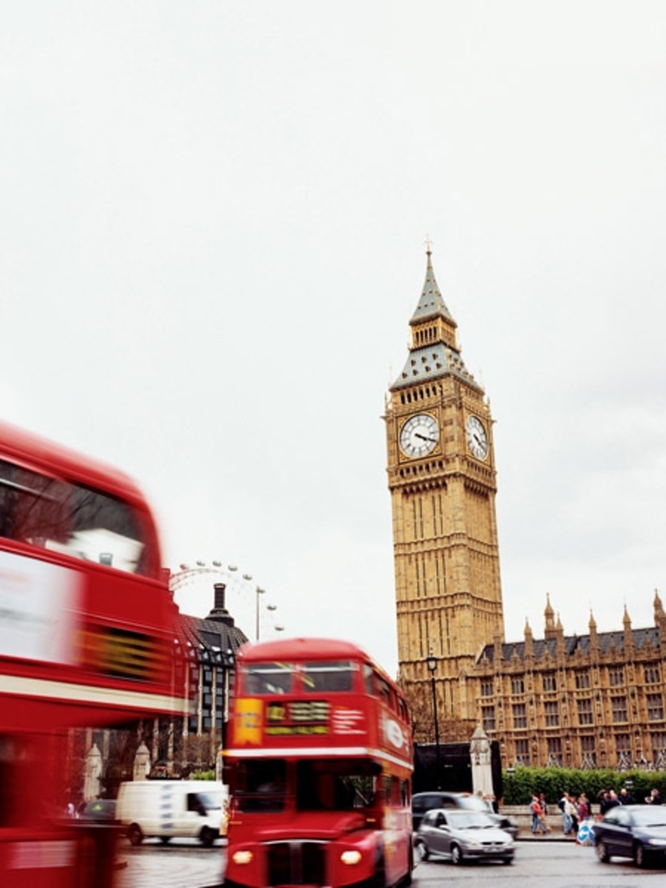 A red double decker bus is driving by Big Ben in London. - London