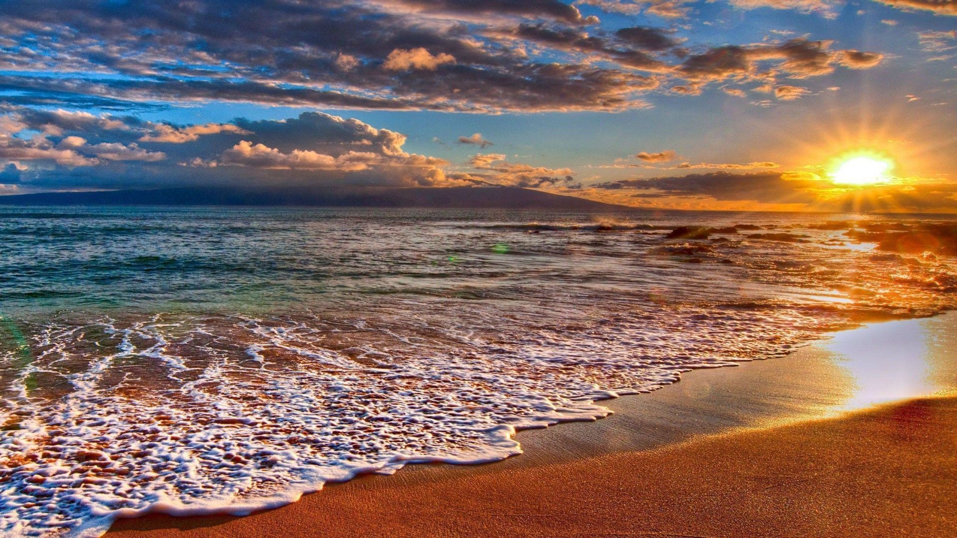 The sun sets over the ocean, with the beach in the foreground and the sky filled with clouds. - Beach, coast, sunset