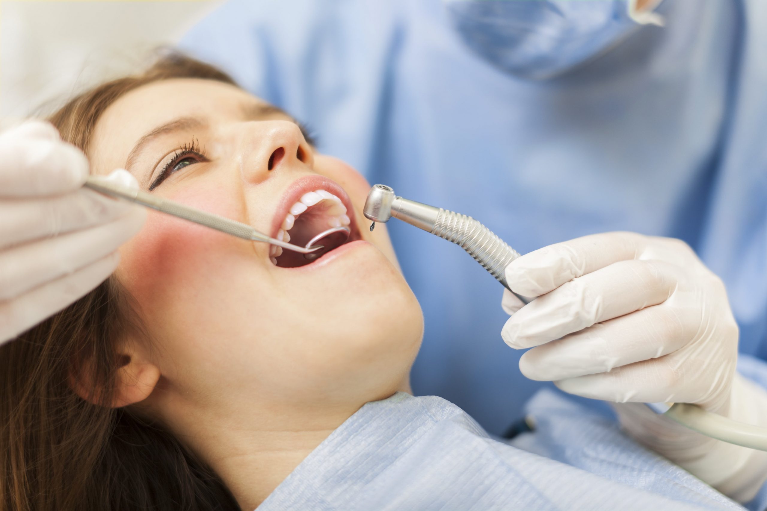 A woman is getting her teeth cleaned at the dentist - Dentist