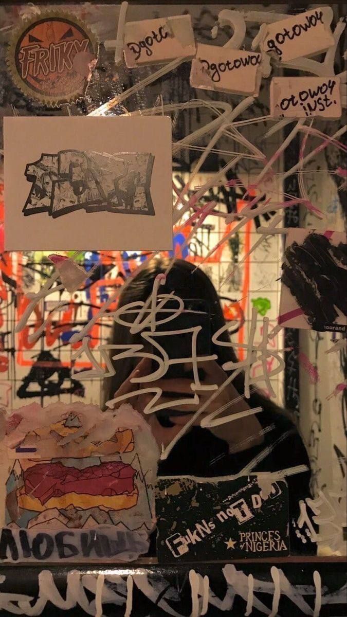 A person standing in front of a wall covered in stickers - Graffiti