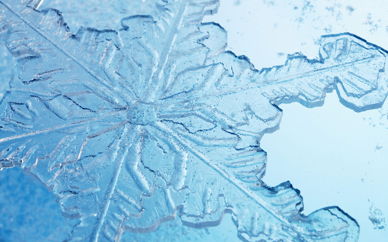 A close up of a snowflake on a blue background - Ice